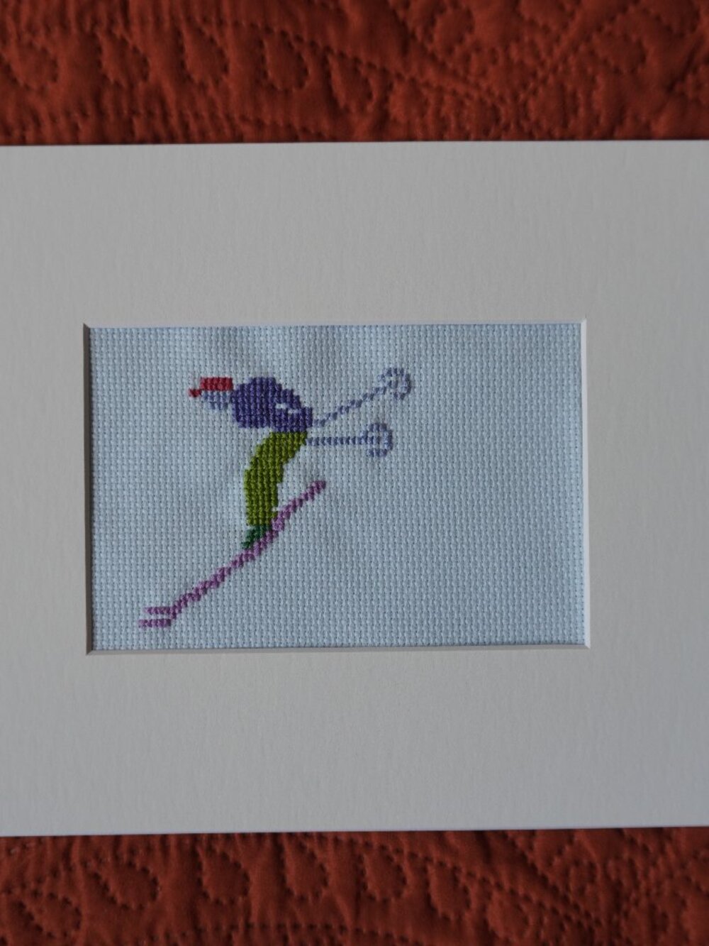 Hand embroidered skier on blue background